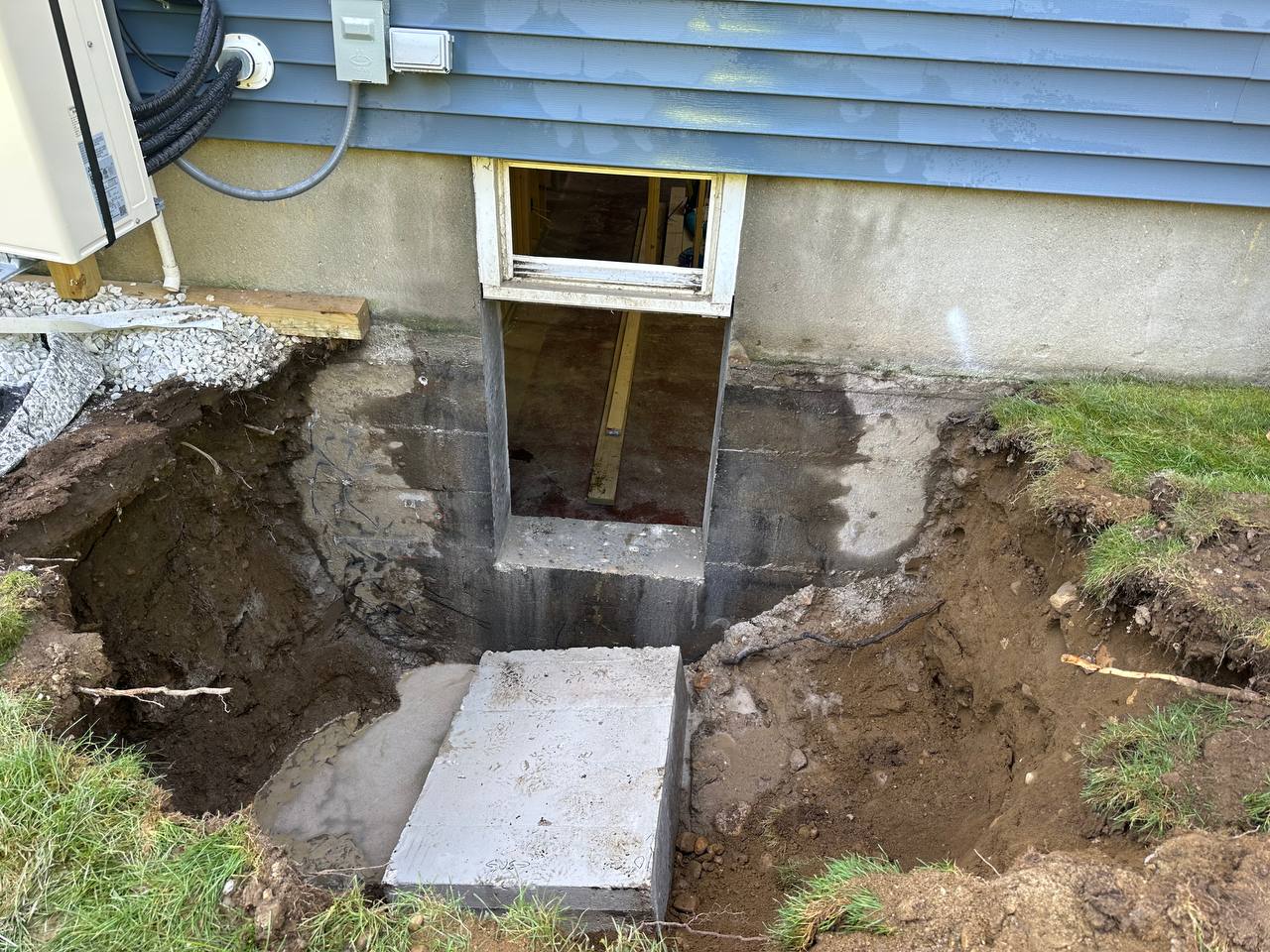 Completed basement egress window opening with exterior stairs and well