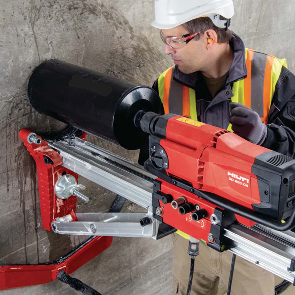 Professional Hilti core drilling rig operator drilling into concrete wall on construction site