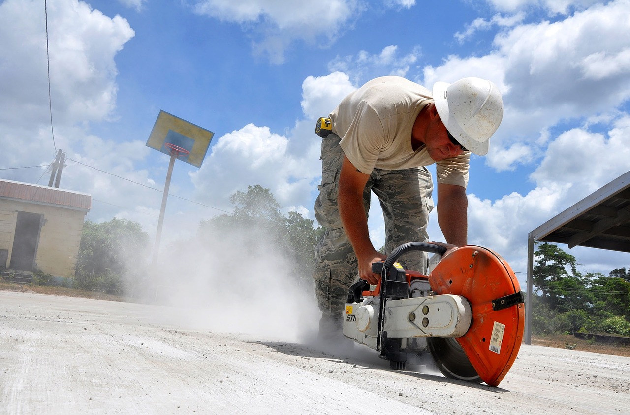 Construction worker using handheld concrete cutoff saw with diamond blade on job site